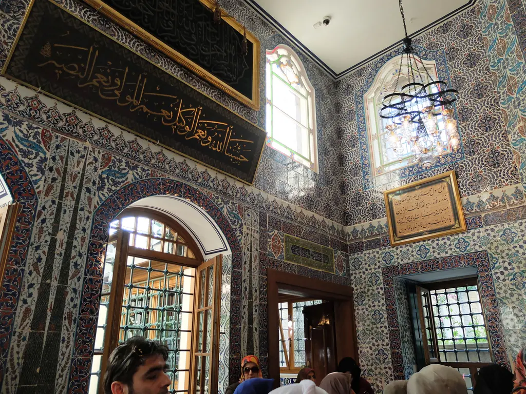 Eyüp Sultan Türbesi'nde iç kapı; çini kaplı duvar, üstünde yazılı levhalar ve ardında gümüş şebekeli sandukaya açılan geçit.