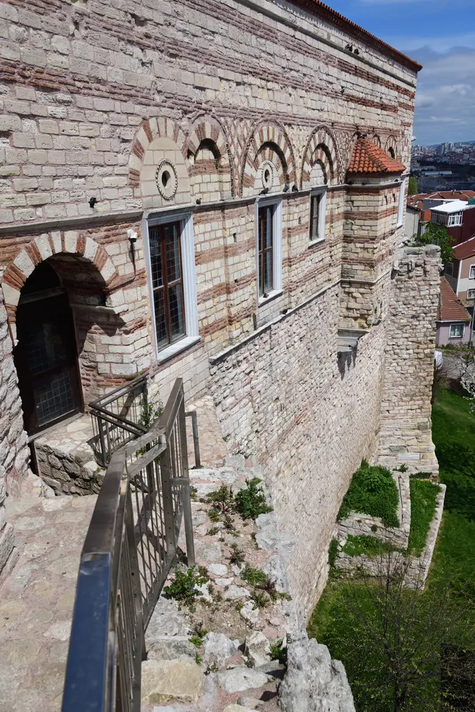 Tekfur Sarayı'nın sur tarafındaki köşesi; duvardan öne taşan konsollar, üzerlerindeki çıkma kalıntısı, kemerli açıklık ve aşağıda dik taş merdiven.