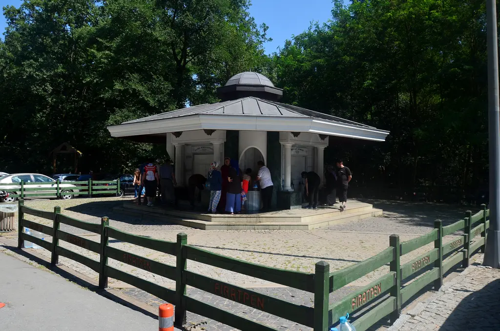 Belgrad Ormanı'nda Neşet Suyu çeşmesi; çatılı çeşme yapısı, önünde ahşap çit ve ağaçlar.