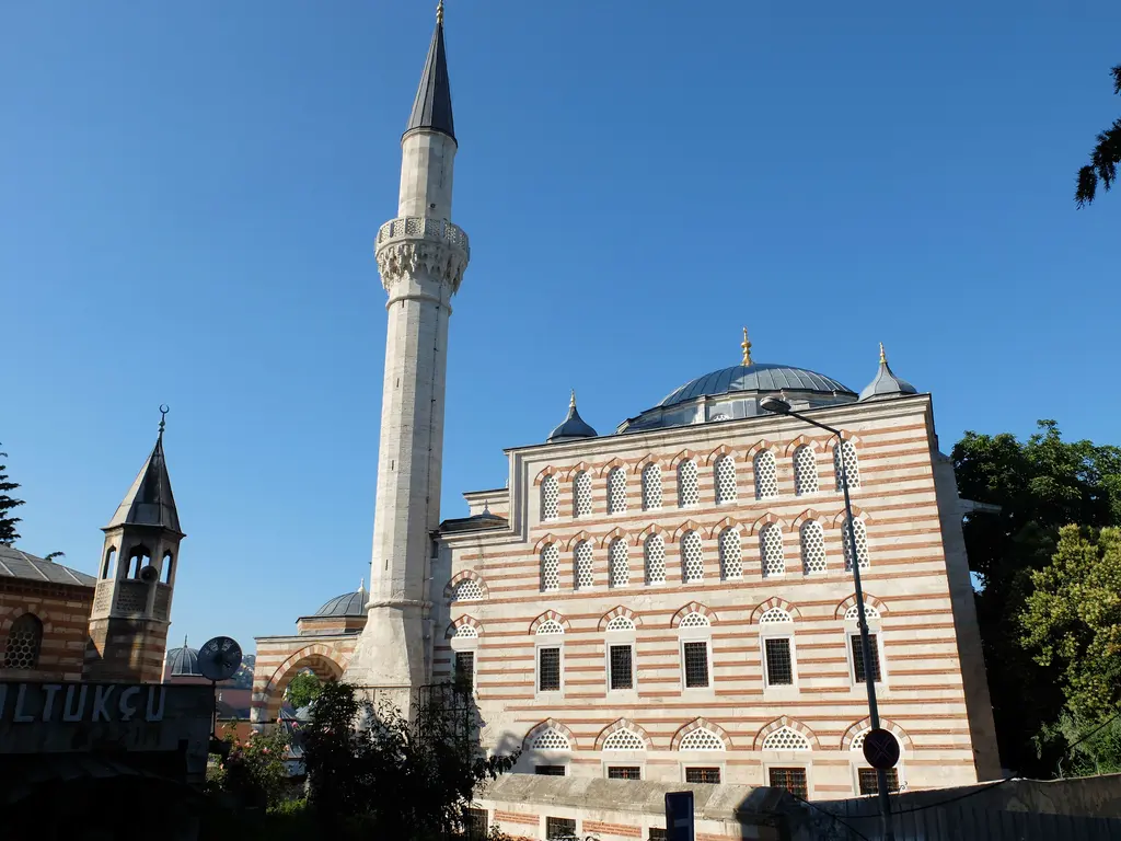 Eyüpsultan'da Zal Mahmud Paşa Camii; taş ve tuğla sıralı yüksek duvarlar, kat kat kemerli pencereler, ince minare ve mavi gökyüzü.