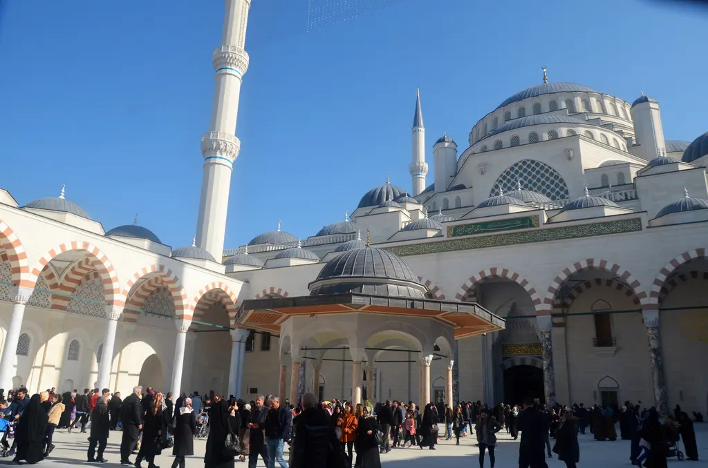 Büyük Çamlıca Camii'nde şadırvan; avlunun ortasında kubbeli şadırvan, arkada revaklar, minareler ve cami.