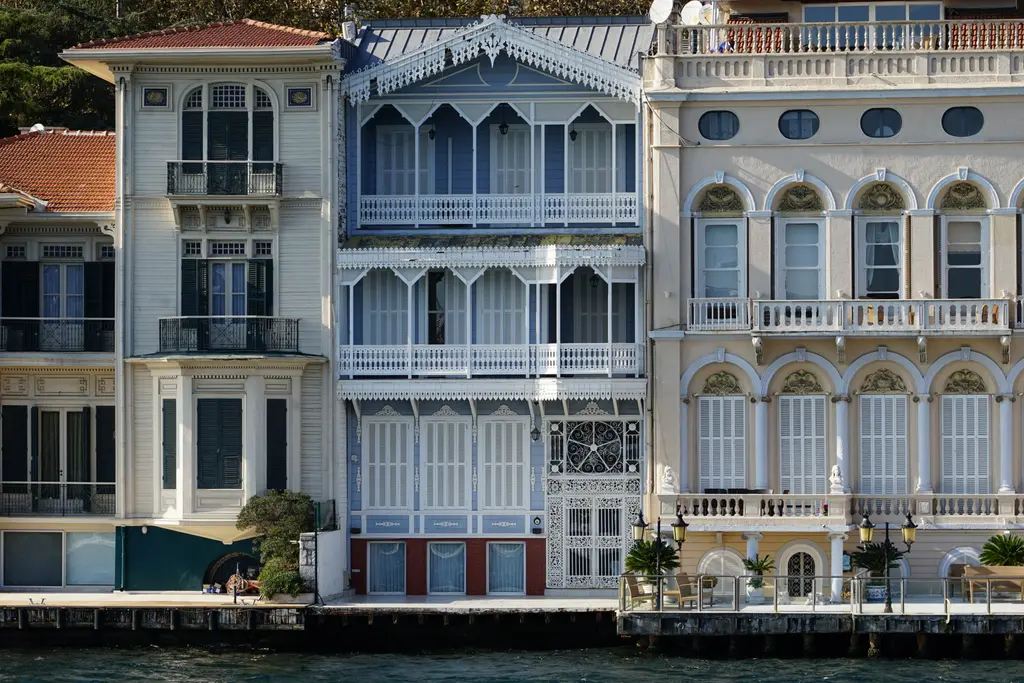 Beyazciyan Yalısı; yan yana iki ahşap yalı, oymalı saçaklar, mavi pencere çerçeveleri ve sağda kemerli taş cephe.