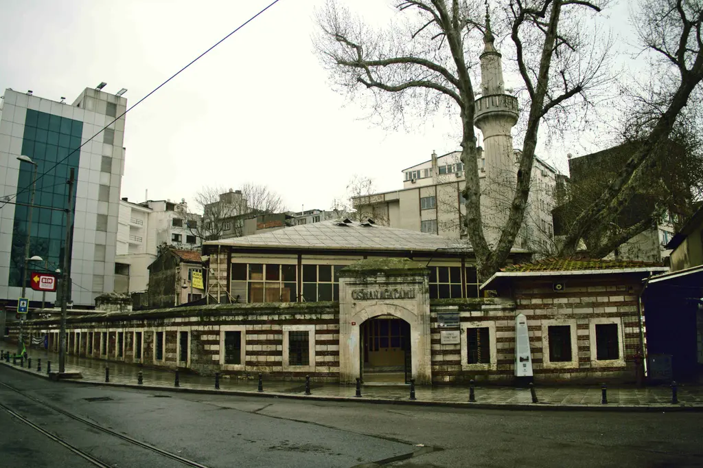 Kadıköy'de Osmanağa Camii; tuğla ve taş almaşık avlu duvarı, kemerli kapı, tek minare ve yaşlı ağaçlar.