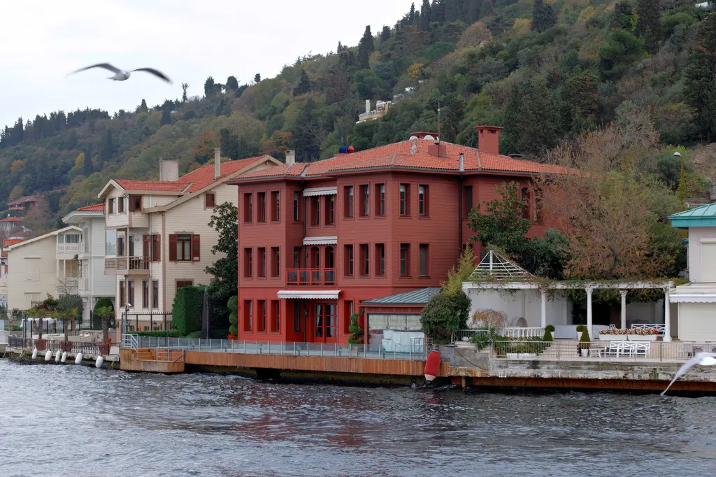 Sadullah Paşa Yalısı'na yakından bakış; kırmızı cephe, sıra pencereler, rıhtım ve yanında beyaz yalılar.