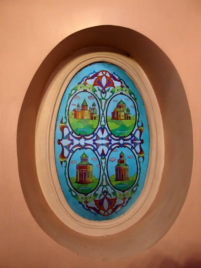 Surp Takavor Kilisesi'nde renkli cam; oval pencerede dört bölümlü kilise tasvirleri ve çiçek motifleri.