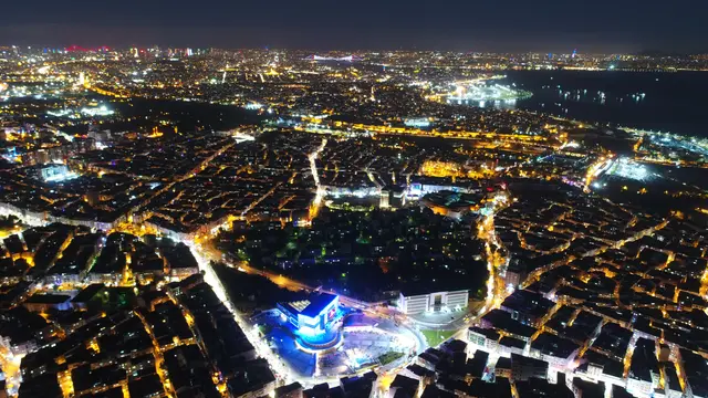 Gece havadan Zeytinburnu; ışıklı sokak ızgarası boyunca sık apartman blokları, ortada aydınlatılmış bir meydan ve arkada Marmara Denizi'nin karanlık şeridi.