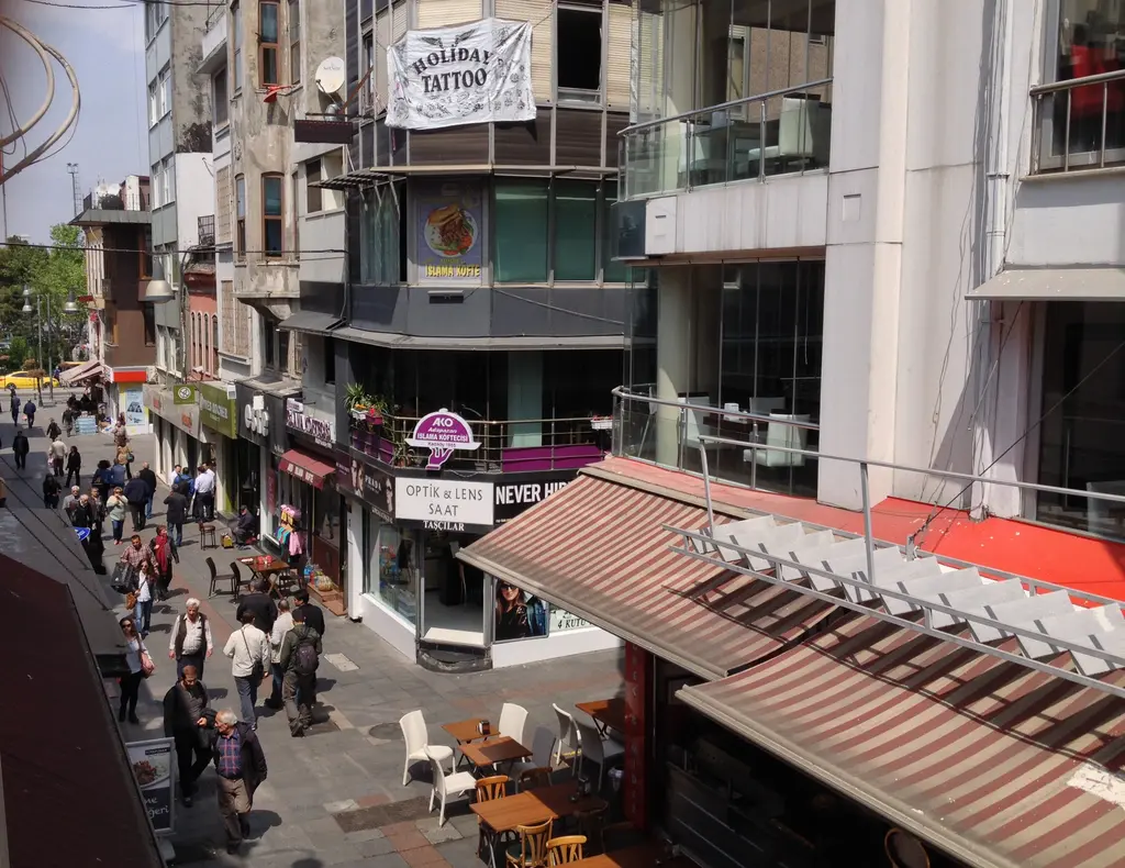Kadıköy Çarşısı yukarıdan; tenteli dükkânlar, sokak masaları, yürüyen insanlar ve çok katlı binalar.