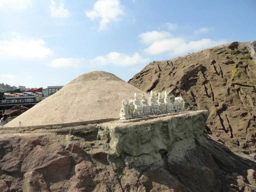 Miniatürk'te Nemrut Dağı maketi; gri bej tümülüs konisi, önündeki terasta sıralı oturan heykeller ve başlar, kızıl kayalık zemin.