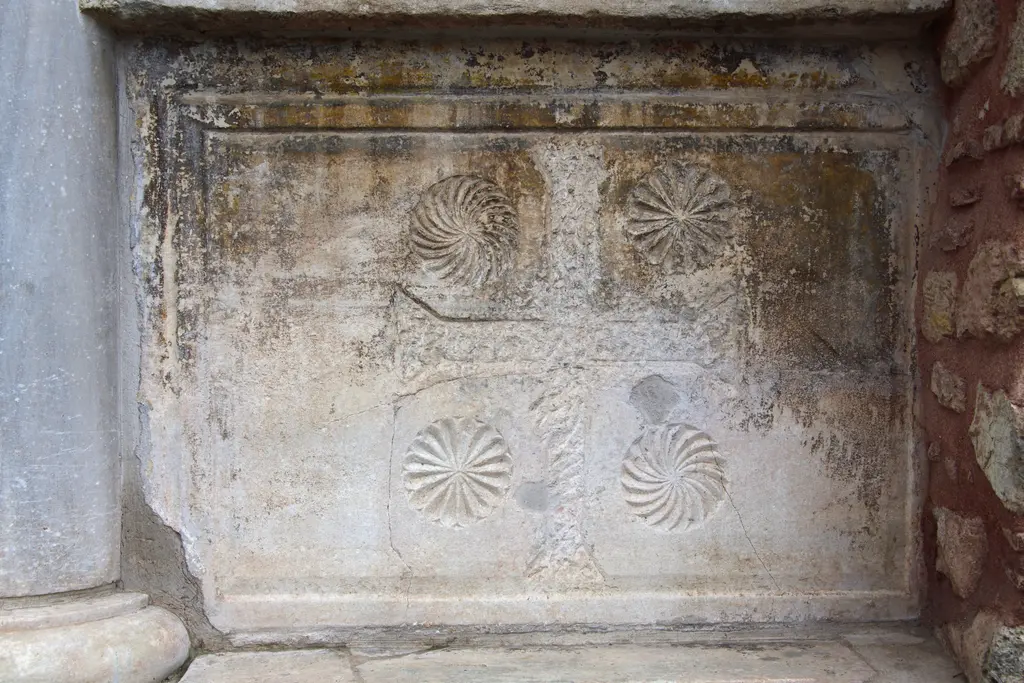 Vefa Kilise Camii'nde daha yıpranmış ikinci levha; silik merkezî motifin çevresinde dört burgu rozet, üst yarıda yosun ve liken lekeleri, alt kenarda çatlak.
