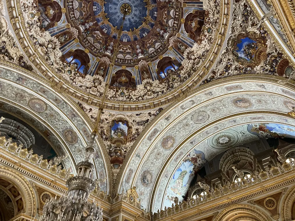 Dolmabahçe Sarayı'nın Muayede Salonu; yüksek kubbe, süslü kemerler, sütunlar ve ortada asılı dev kristal avize.