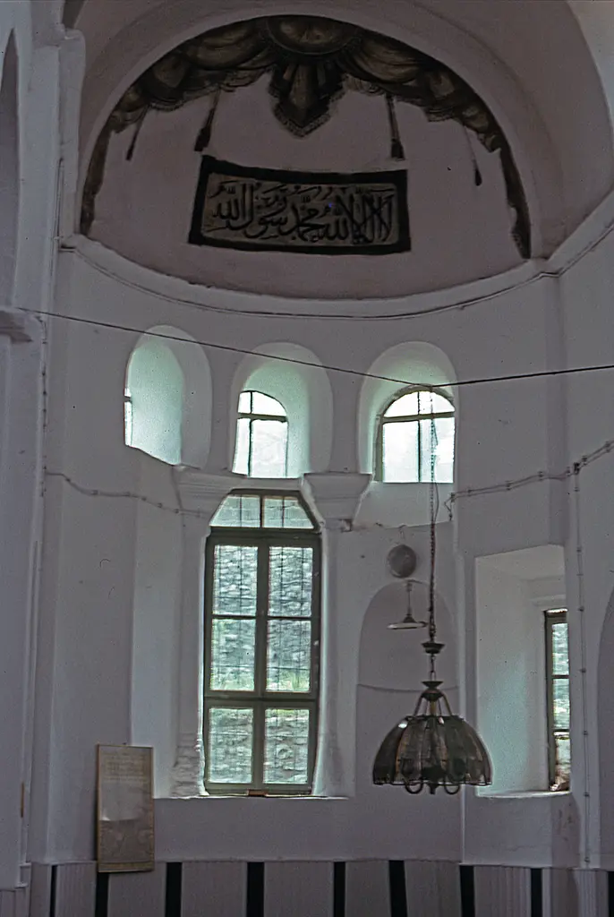 Vefa Kilise Camii'nde badanalı iç mekân; yarım kubbeli niş, üstünde koyu renkli perde ve püskül bezemesi, asılı hat levhası, kemerli pencereler ve cam abajurlu avize.