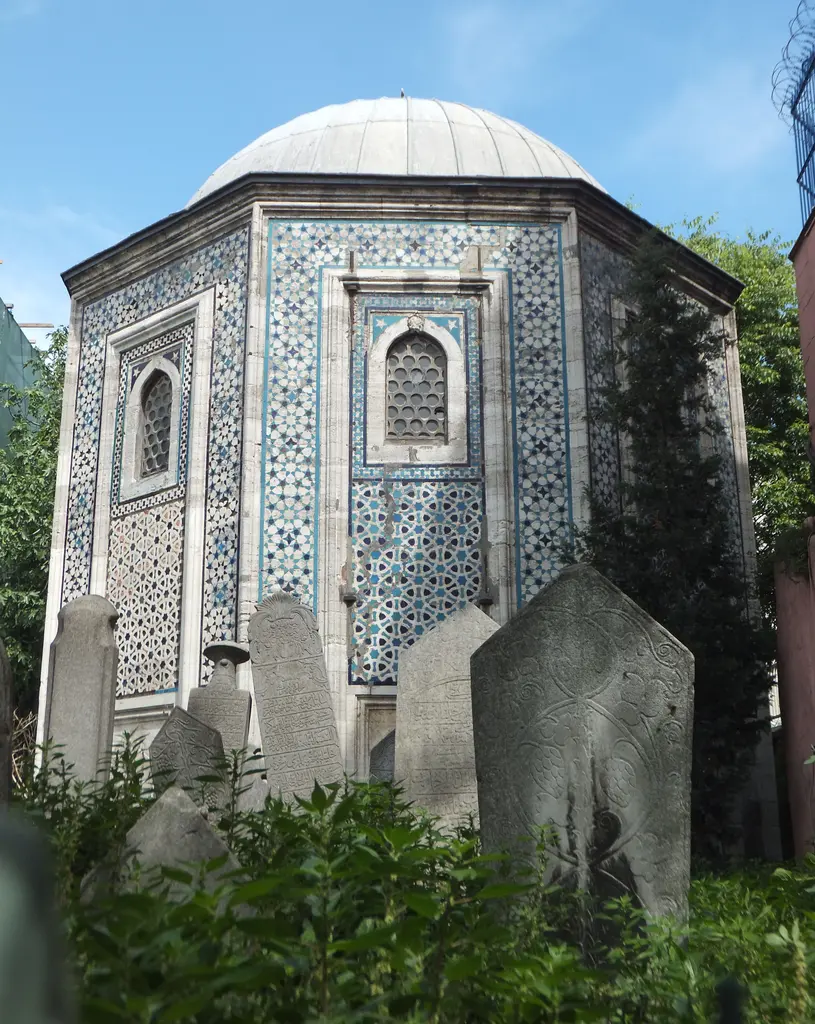 Mahmut Paşa Türbesi ve hazire; önde ağaçlar arasında sarıklı ve kavuklu mezar taşları, arkada çinili sekizgen gövde ve kubbe.