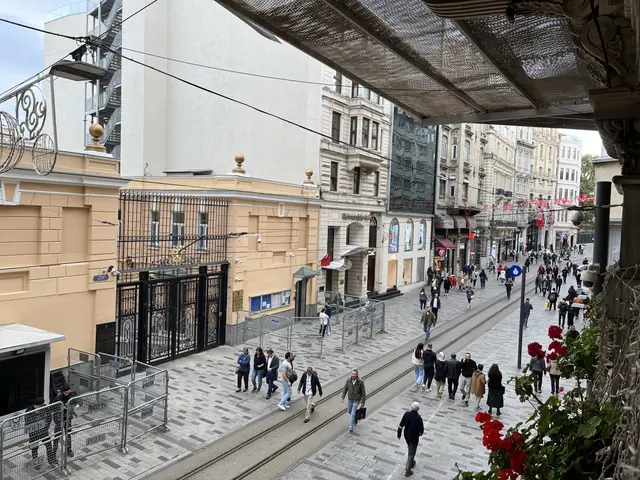 Yukarıdan İstiklal Caddesi; solda altın kartallı demir kapısıyla Rus Başkonsolosluğu, önünde polis bariyerleri ve tramvay rayları.