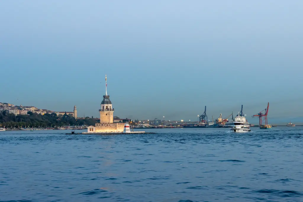 Boğaz'da Kız Kulesi; ortada küçük kule, yanında geçen vapur, arkada Anadolu yakasının kıyısı ve liman vinçleri.
