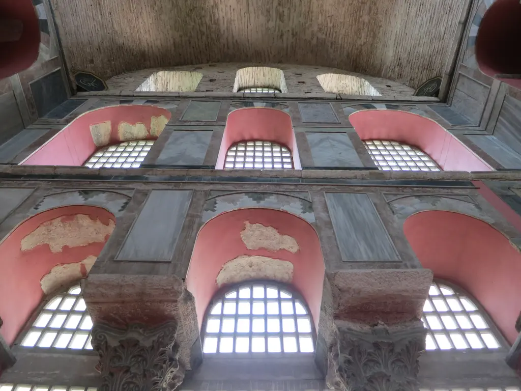 Kalenderhane Camii'nde yüksek duvar; altta oymalı sütun başlıkları arasında kemerli pencereler, üstte ikinci pencere sırası ve tuğla tonoz.