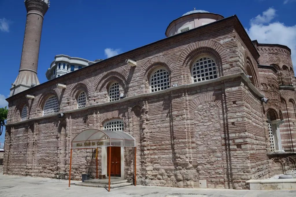 Fatih'te Fenari İsa Camii'nin güney cephesi; iki sıra kemerli şebekeli pencere, tuğla ile taşın almaşık örgüsü, solda tuğla minare ve sağda pembe kasnaklı kubbe.