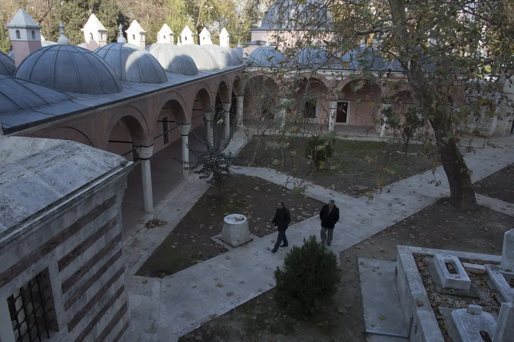 Zal Mahmud Paşa Külliyesi'nin alt bahçesi; yukarıdan bakışla kurşun kubbeli medrese odaları, revaklar, ağaçlar ve yürüyen iki kişi.