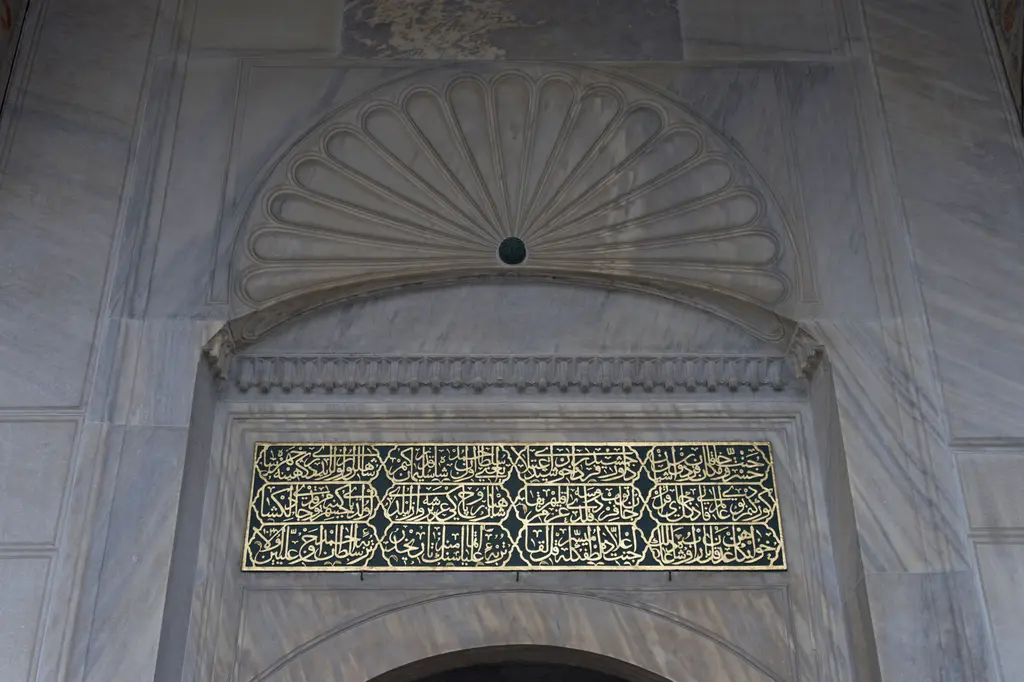 Sultan Ahmed Türbesi'nin kapısı; mermer üzerinde istiridye kabuğu biçimli alınlık, altında siyah zemin üzerine altın yaldızlı yazılı kitabe.