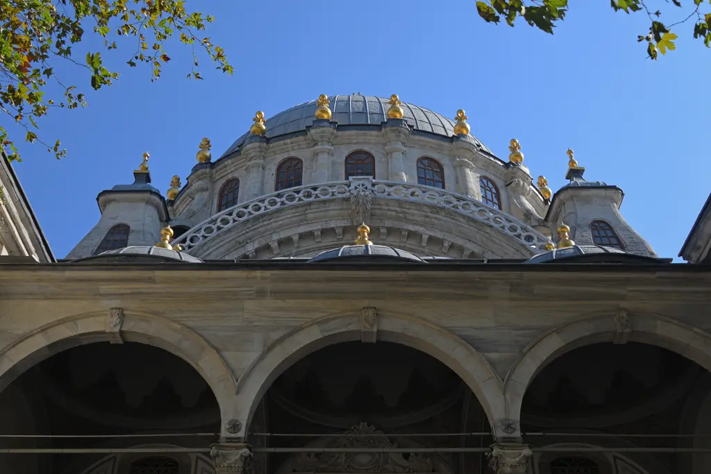 Nusretiye Camii'nin cephesi; gri kurşun kubbe, barok kıvrımlı kemerler, taş korkuluklar ve iki ince minare.