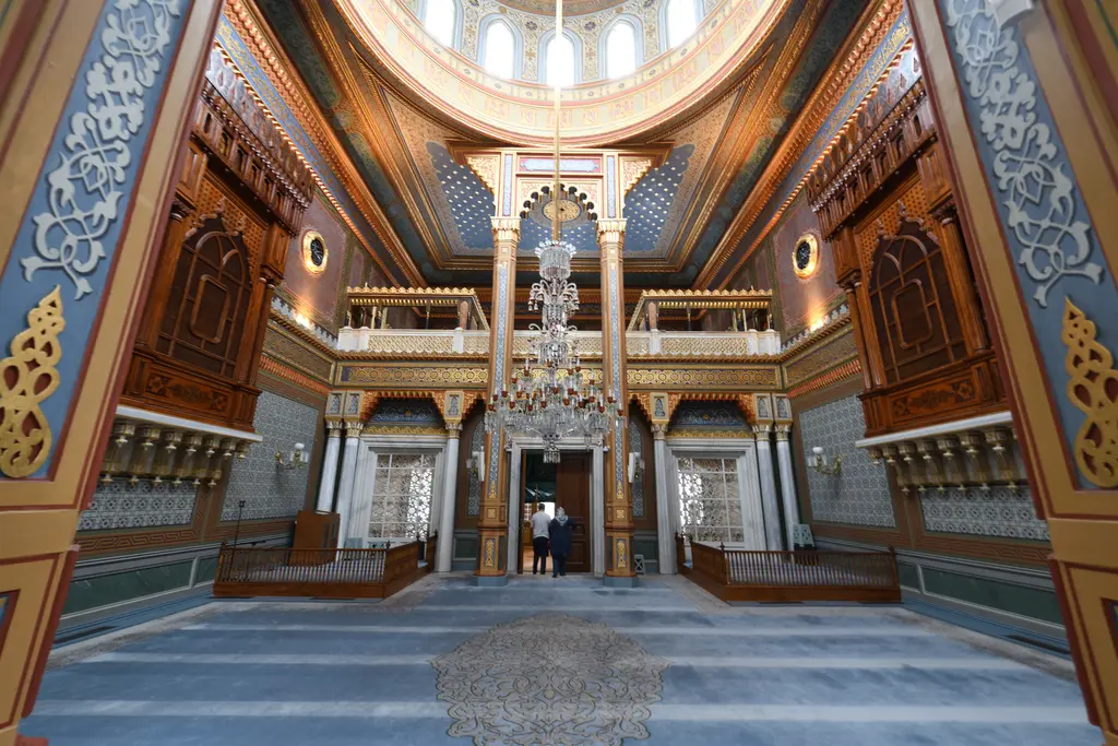 Yıldız Hamidiye Camii'nin harimi; ortada kristal avize, iki yanda ahşap mahfiller, oymalı kolonlar ve mavi halı.