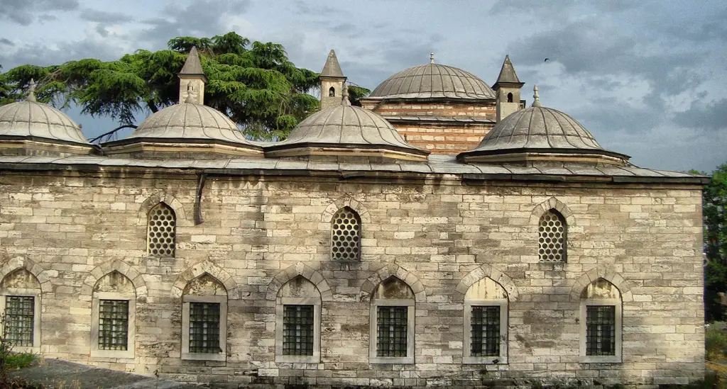 Medrese binası dışarıdan; sıra sıra kurşun kaplı küçük kubbeler, almaşık taş duvar, kemerli pencereler ve önündeki ağaçlar.