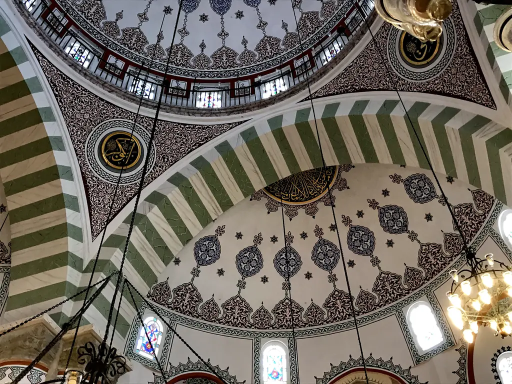 Mihrimah Sultan Camii'nde yarım kubbe; kırmızı beyaz kemer, kalem işli yüzeyler ve renkli camlı pencereler.