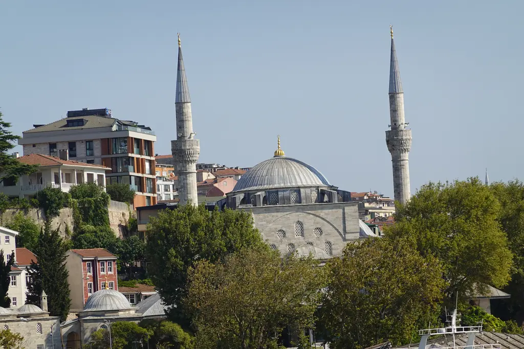 Üsküdar'da Mihrimah Sultan Camii; çift minareli kubbeli cami, önünde geniş son cemaat yeri, ağaçlar ve iskele meydanı.