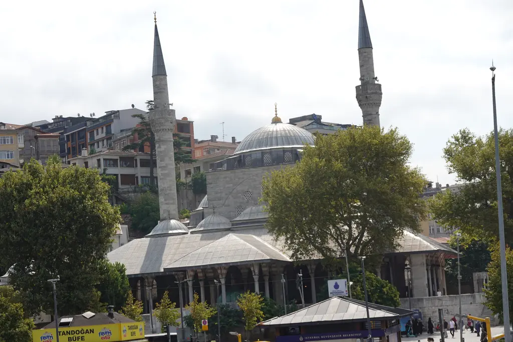 Üsküdar'da Mihrimah Sultan Camii; kıyıda iki minareli kubbeli cami, önünde ağaçlar, arkasında yamaçtaki binalar.