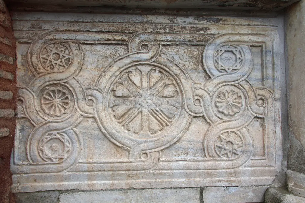 Vefa Kilise Camii'nde mermer korkuluk levhası yakın plan; ortada büyük tekerlek rozet, çevresinde dört küçük yıldız, madalyonu dolaşan örgülü bant ve profilli çerçeve.