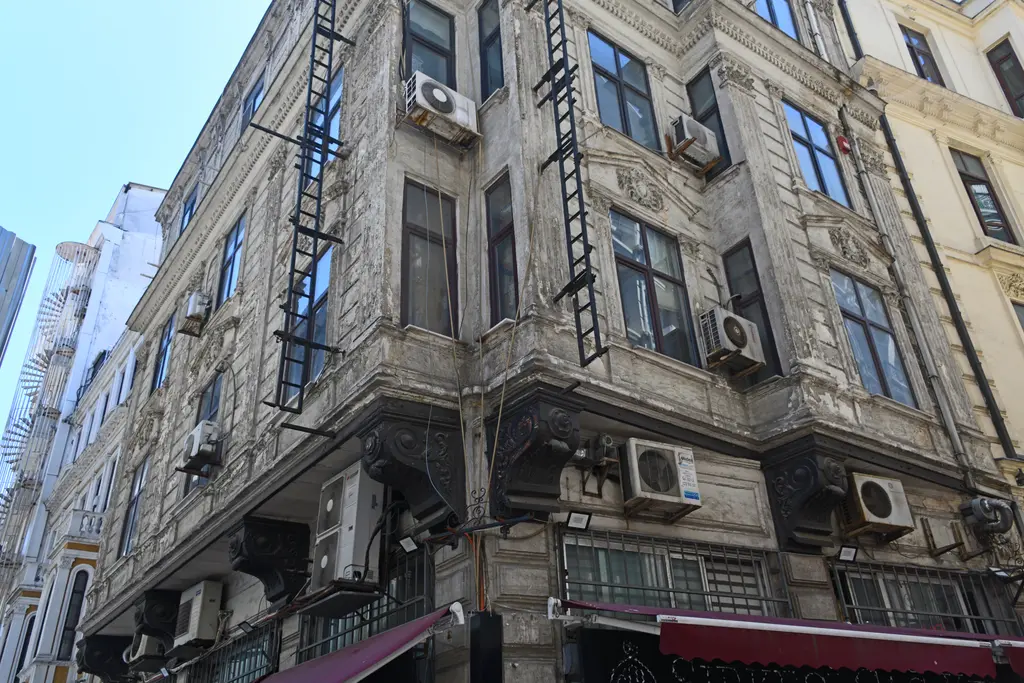 Eminönü'nde Piri Reis Sokağı'ndaki eski iş hanı; yüksek taş cephe, demir balkonlar, klimalar ve sokak tabelaları.