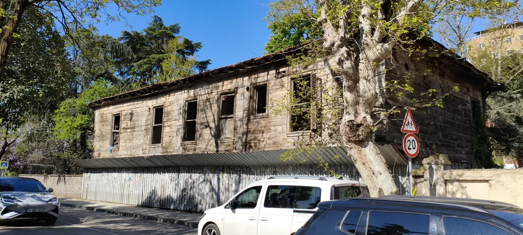 Göztepe'de Rıdvan Paşa Selamlık Köşkü; boyası dökülmüş uzun ahşap yapı, kırık pencereler ve önünde çınar ağacı.