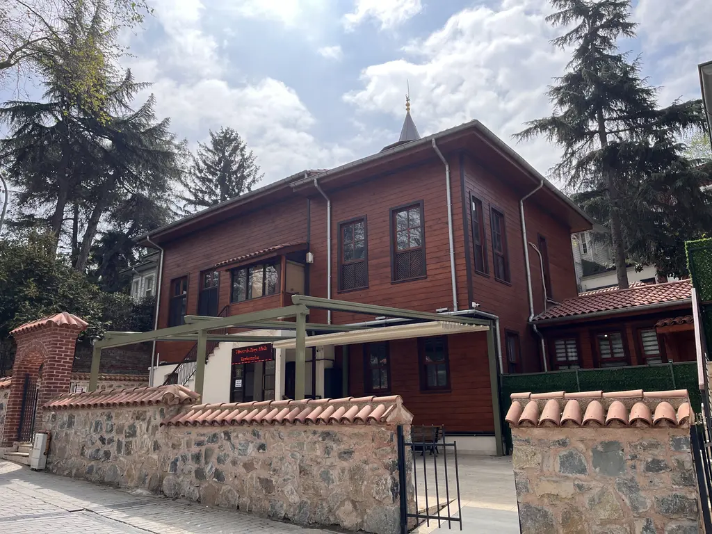 Çengelköy'de Şeyh Nevruz Camii; kahverengi ahşap kaplı yapı, kiremit çatı, küçük minare ve taş bahçe duvarı.