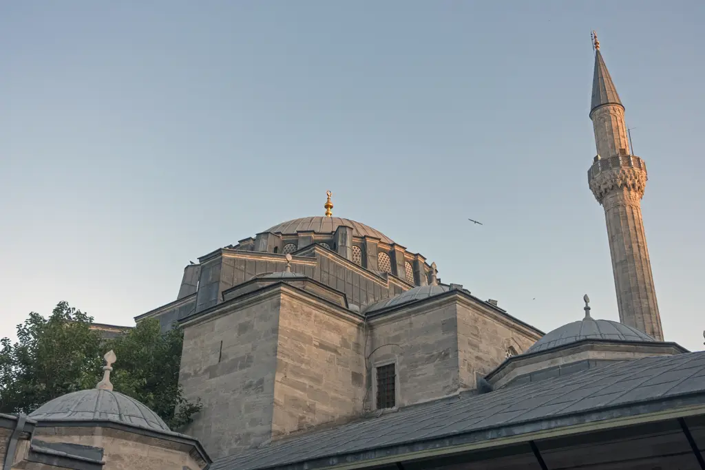 Kılıç Ali Paşa Camii'nin kubbesi ve minaresi; kesme taş kasnak, kurşun kaplı kubbe, yanında ince sivri külahlı minare ve önde küçük kubbeler.