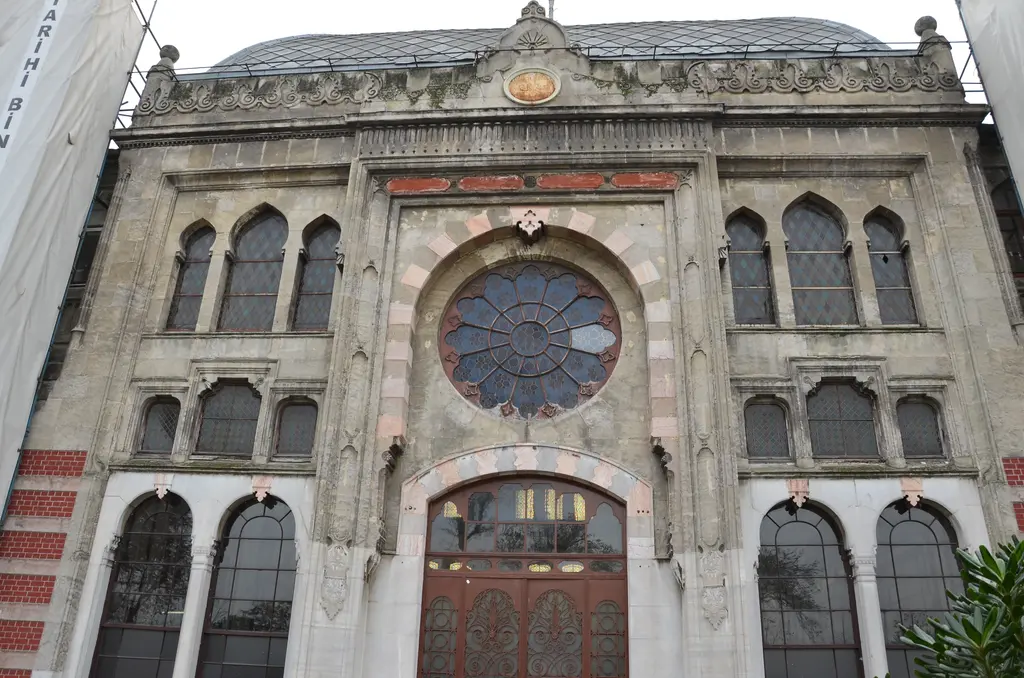Sirkeci Garı'nın ana kapısı alçak açıdan; ışınsal taş kafesli gül pencere, pembe ve krem taşlarla örülü kemer, üstte sivri kemerli dar pencereler ve altta oymalı kahverengi ahşap çift kapı.