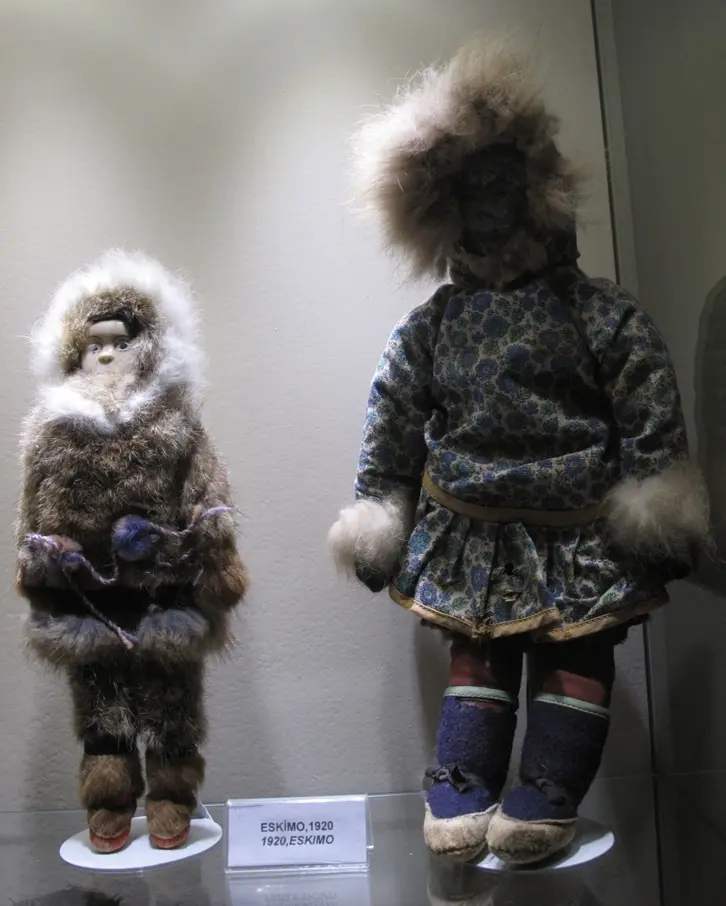 İstanbul Oyuncak Müzesi'nde Eskimo bebekleri; kürk giysili ve kapüşonlu iki bez bebek, beyaz vitrin ve etiket.