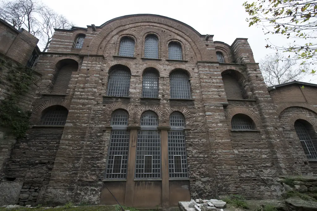 Kalenderhane Camii'nin kuzey cephesi; üç sıra kemerli parmaklıklı pencere, taş ve tuğla almaşık duvar ve önde yığılı taşlar.