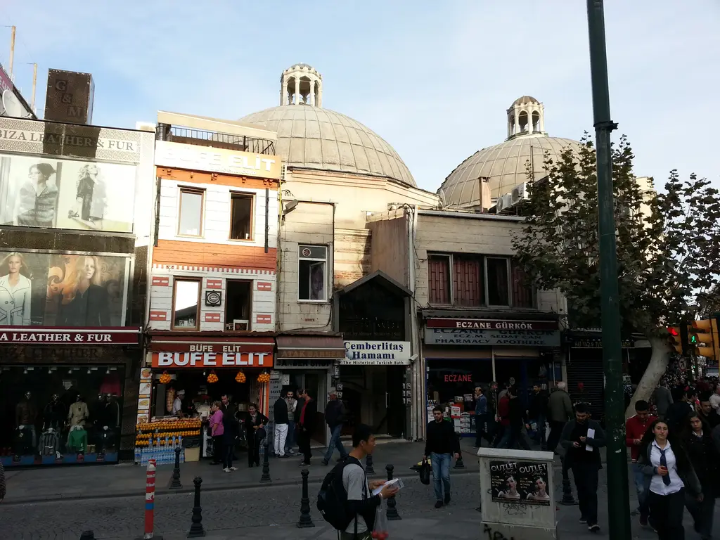 Çemberlitaş Hamamı'nın iki kubbesi; kurşun kaplama, kubbe yüzeyindeki cam aydınlıklar, altta dükkân cepheleri ve hamamın tabelası.