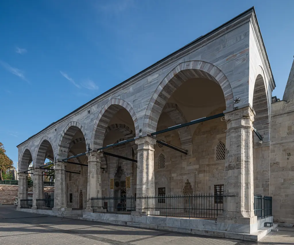 Mahmut Paşa Camii'nin son cemaat revakı; kalın taş payelere oturan sivri kemerler, demir gergiler, kurşun çatı ve önde geniş taş zemin.