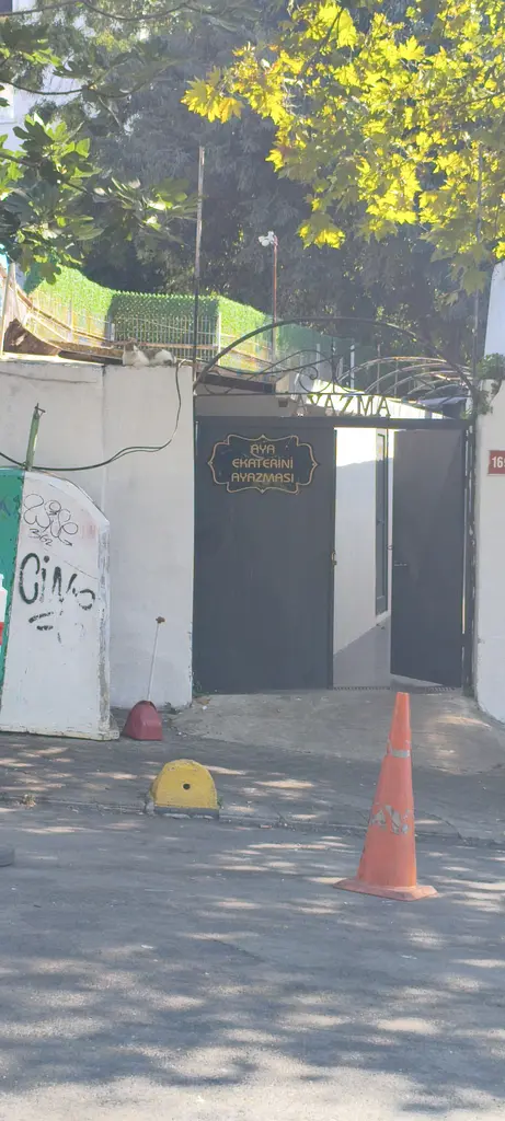 Moda'da Aya Ekaterini Ayazması'nın girişi; beyaz duvarda kapı, yanında ağaç ve önde trafik konisi.