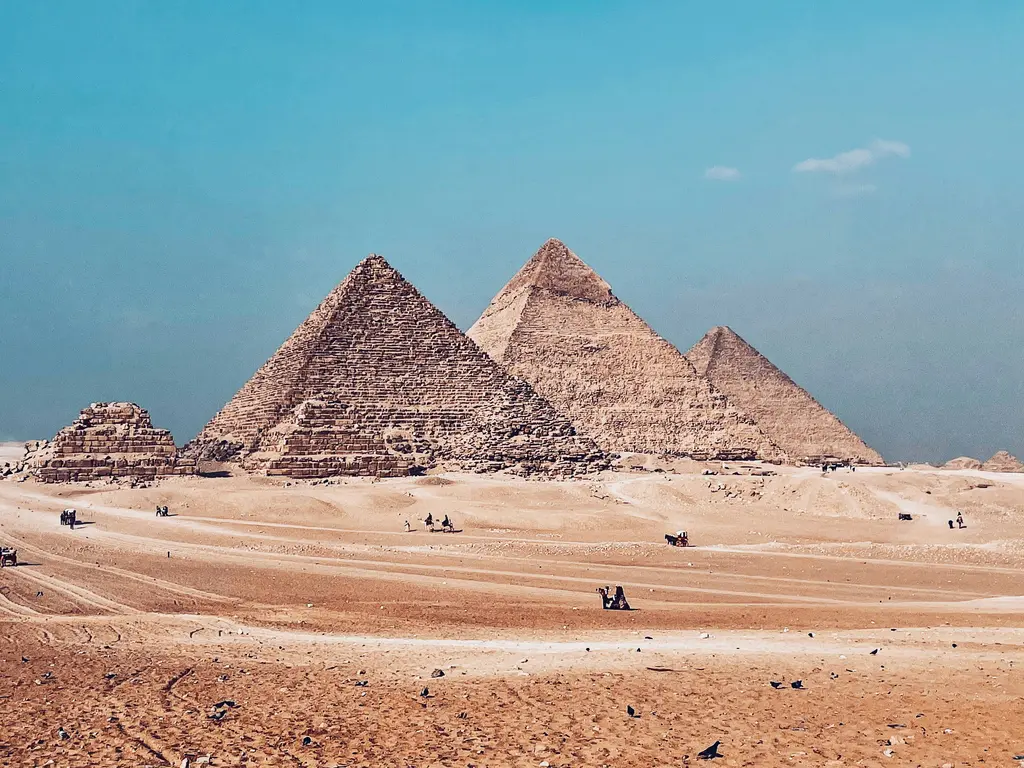 Giza'da piramitler; çölün kenarında yükselen üç büyük piramit ve önlerindeki kum düzlüğü.