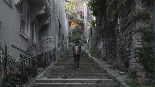 Firuzağa'da taş basamaklı dik bir yokuş; iki yanda duvarlar ve bitkiler, yukarı çıkan bir yaya.