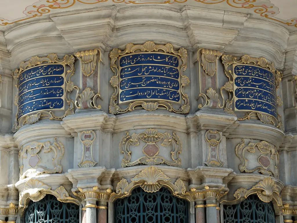 Mihrişah Valide Sultan Sebili'nde kitabeler; mavi zemin üzerinde yaldızlı yazılı paneller, mermer kartuşlar ve barok kıvrımlı silmeler.
