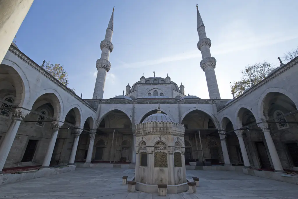 Yeni Valide Camii'nin avlusu; şadırvan, iki yanda yükselen ince minareler, revaklar ve arkada kubbe.