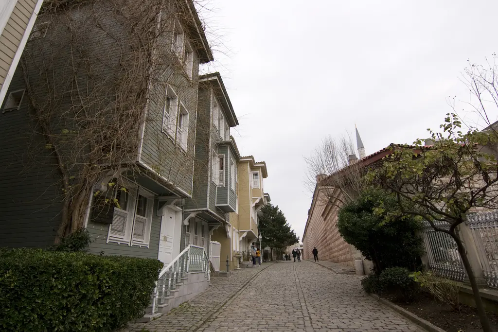Soğukçeşme Sokağı'nda yokuş; solda yeşil ve sarı ahşap evler ile giriş merdivenleri, sağda duvar, çitler ve yapraksız ağaçlar.