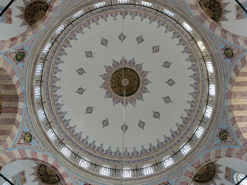Nişancı Mehmed Paşa Camii'nin ana kubbesi içten; beyaz zemin, kırmızı yıldız motifleri, altın göbek ve kasnağı çeviren pencere dizisi.