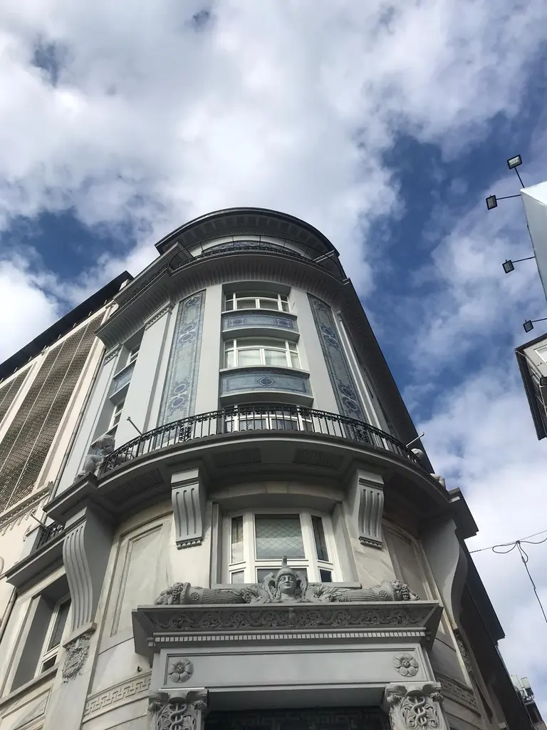 Bankalar Caddesi'nde Minerva Han; köşeyi saran yuvarlak cephe, balkonlu katlar ve bulutlu gökyüzü.