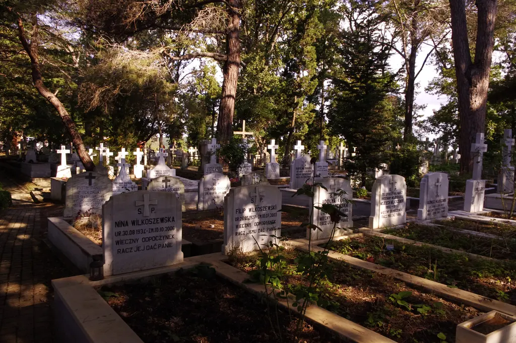 Polonezköy Katolik mezarlığında ağaçların gölgesinde sıralanan beyaz mermer mezarlar ve haçlar, Lehçe yazıtlı taşlar.