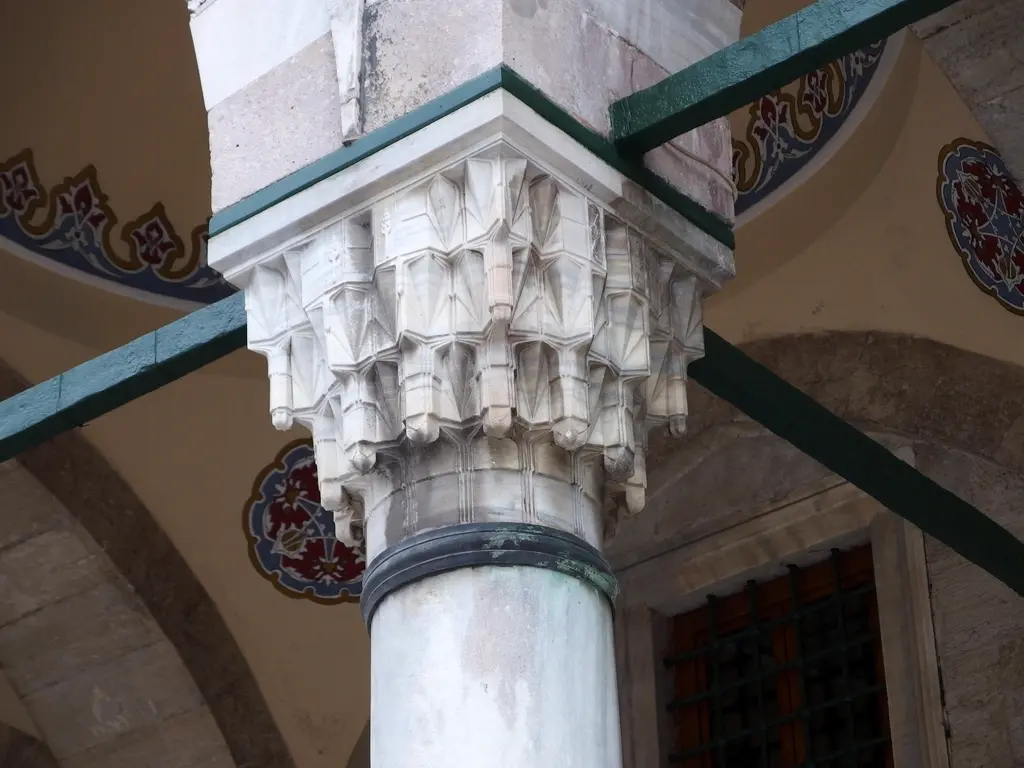 Sokullu Mehmed Paşa Camii'nde sütun başlığı; mukarnaslı beyaz mermer başlık, üstündeki kemer başlangıcı ve iki yanda kalem işi bezeme.