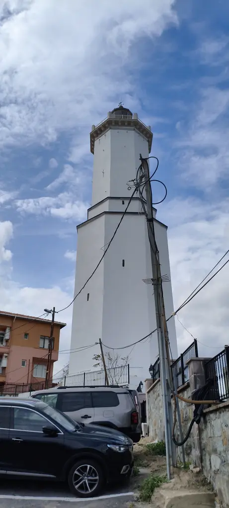 Rumelifeneri'nde fener kulesi; aşağıdan bakılan beyaz kule, tepesinde lamba odası ve önde park etmiş araçlar.