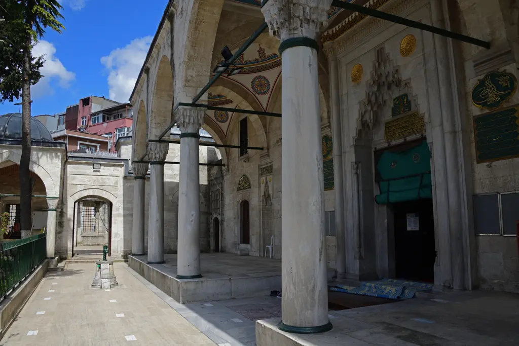 Nişancı Mehmed Paşa Camii'nin son cemaat yeri; mermer sütunlar, mukarnaslı taçkapı, üstünde yazı levhaları ve solda avluya açılan kapı.